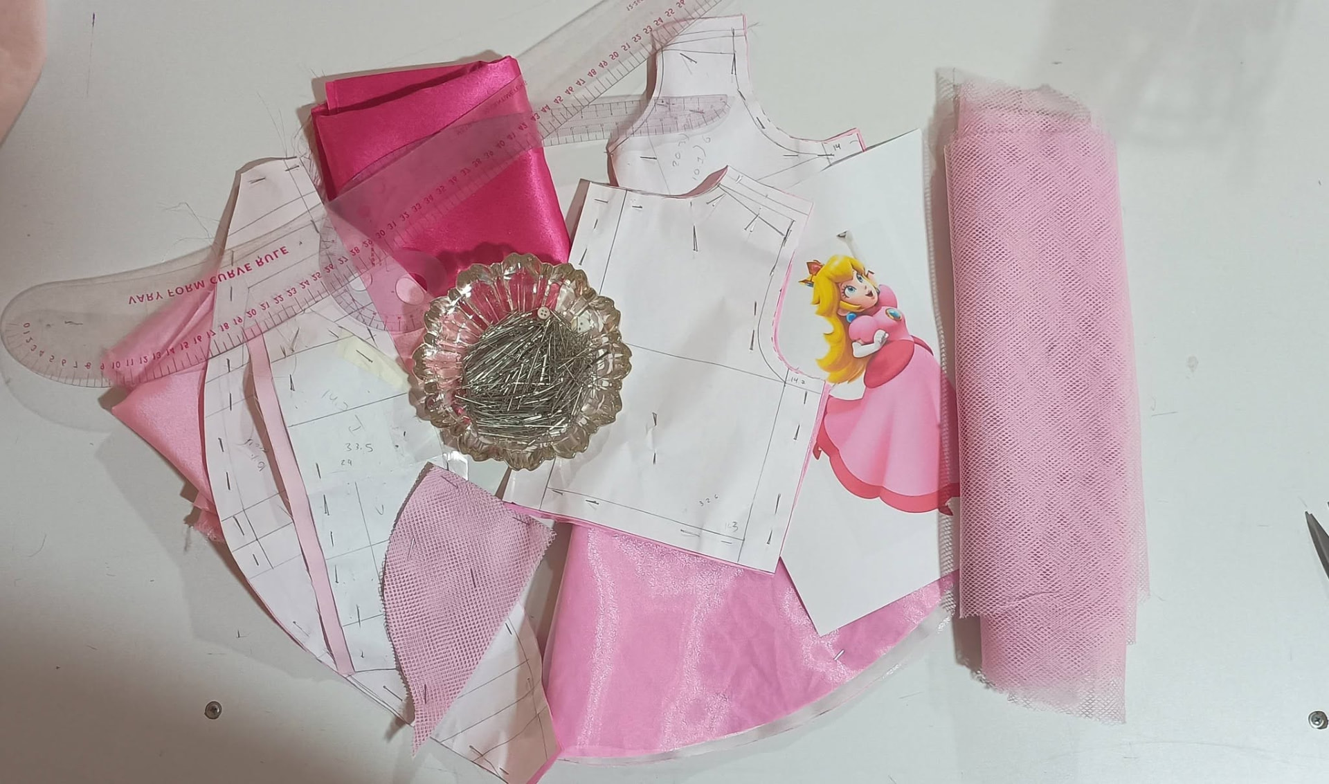Patrones, alfileres y telas rosas en la mesa de corte